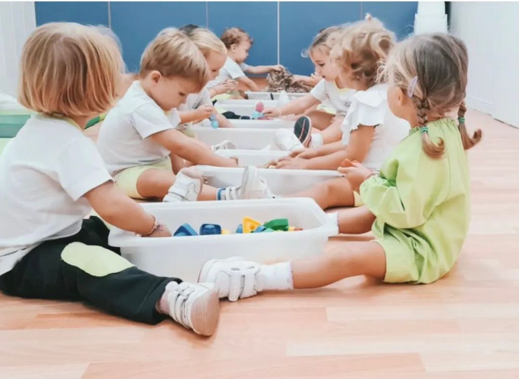 Niños jugando por parejas con cajas llenas de bloques