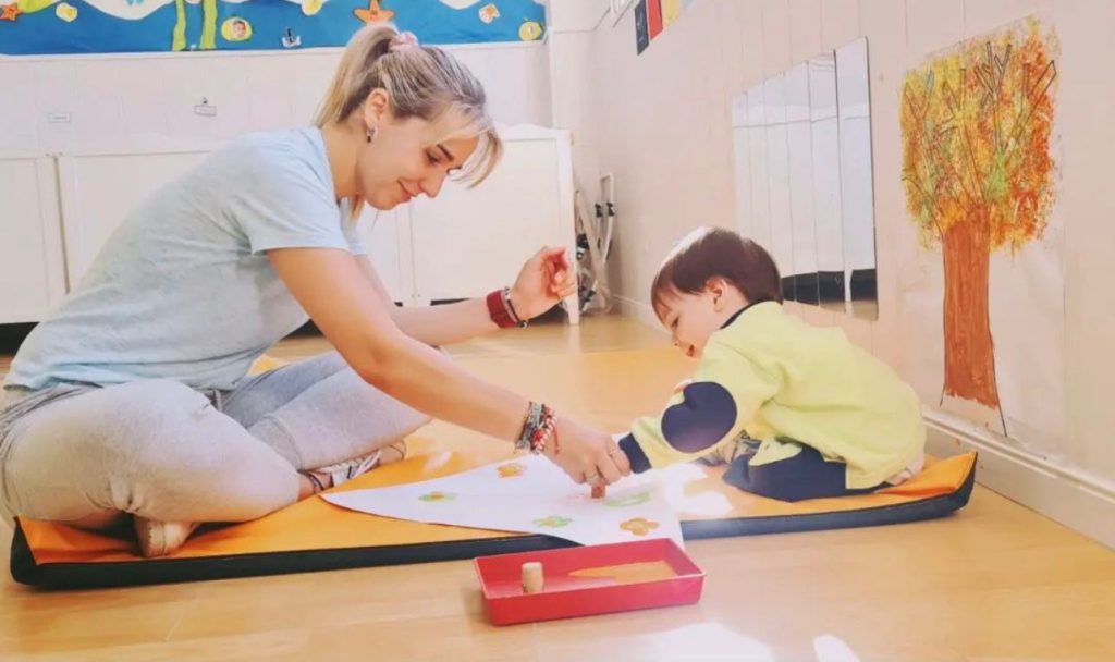 Maestra enseñando a pintar a un niño